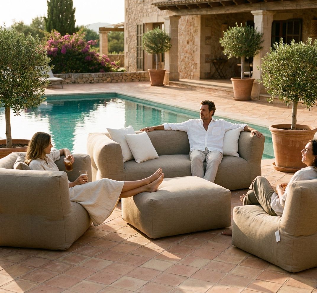 Drie mensen loungend op een complete NOMAD set in zandkleurige outdoorstof aan het zwembad van een mediterraan landhuis