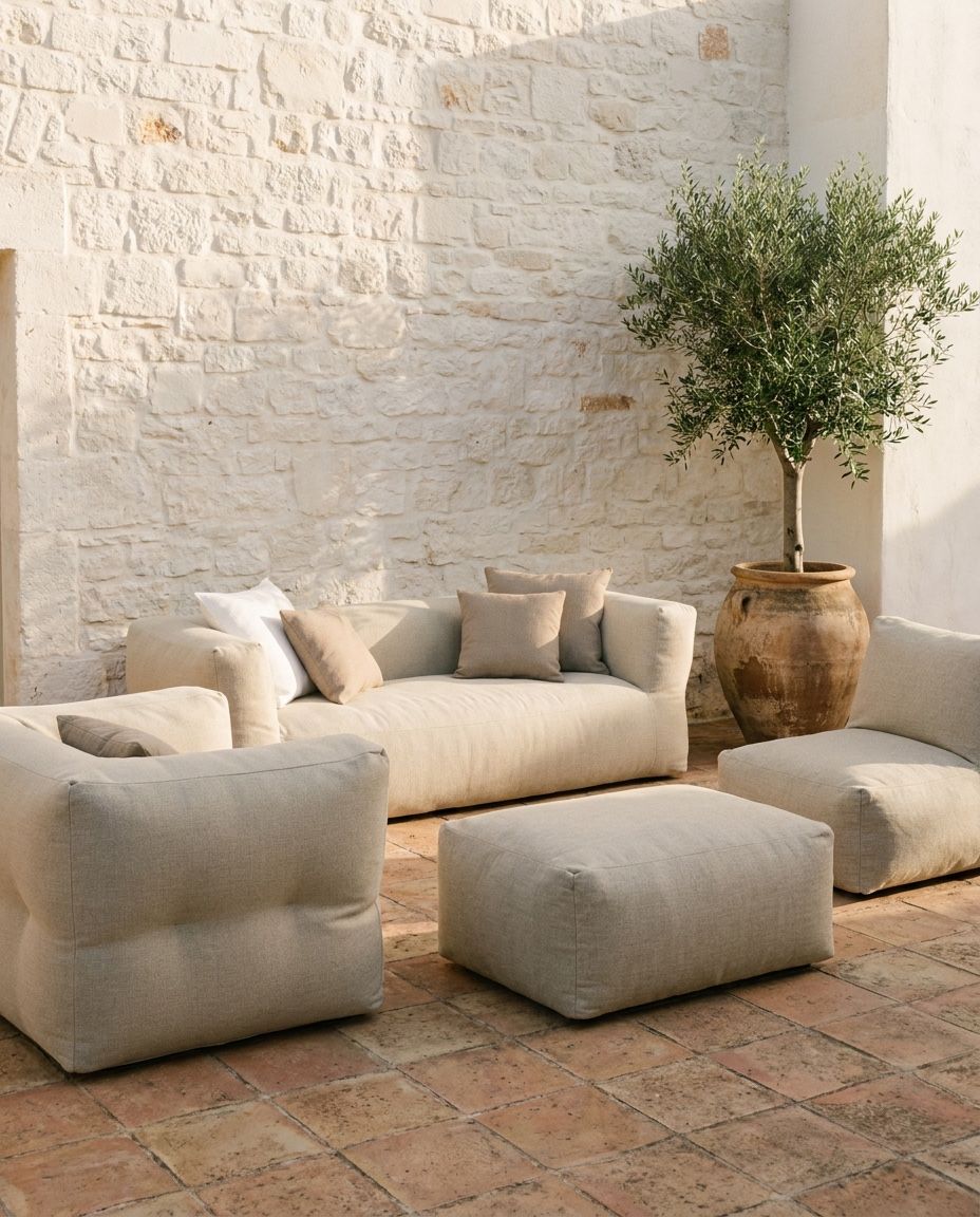 NOMAD loungeset in Copacobana Beige op een terracotta terras bij een witte natuurstenen muur met olijfboom