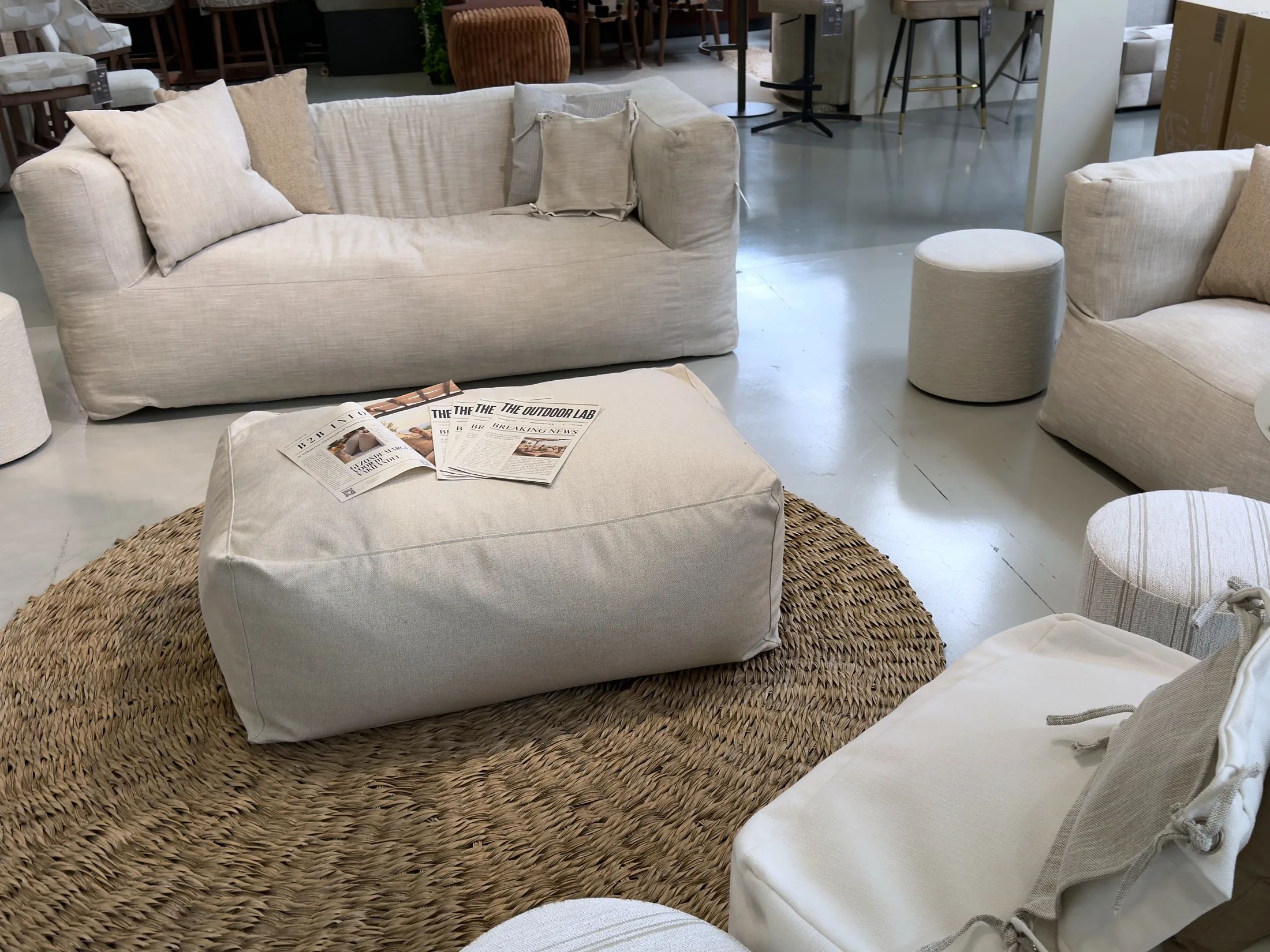 Loungebank en poef van The Outdoor Lab met kranten van het merk op een rond jute kleed in de hal van TICA Aalsmeer