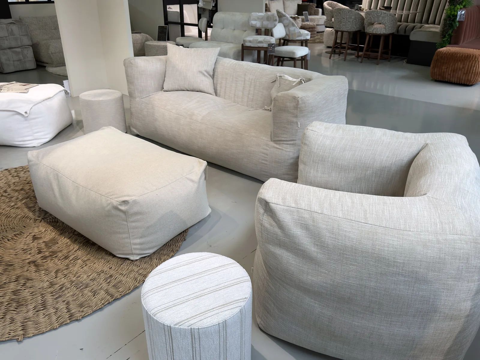 Loungebank, fauteuil en poef van The Outdoor Lab op een rond jute kleed in de hal van TICA Aalsmeer