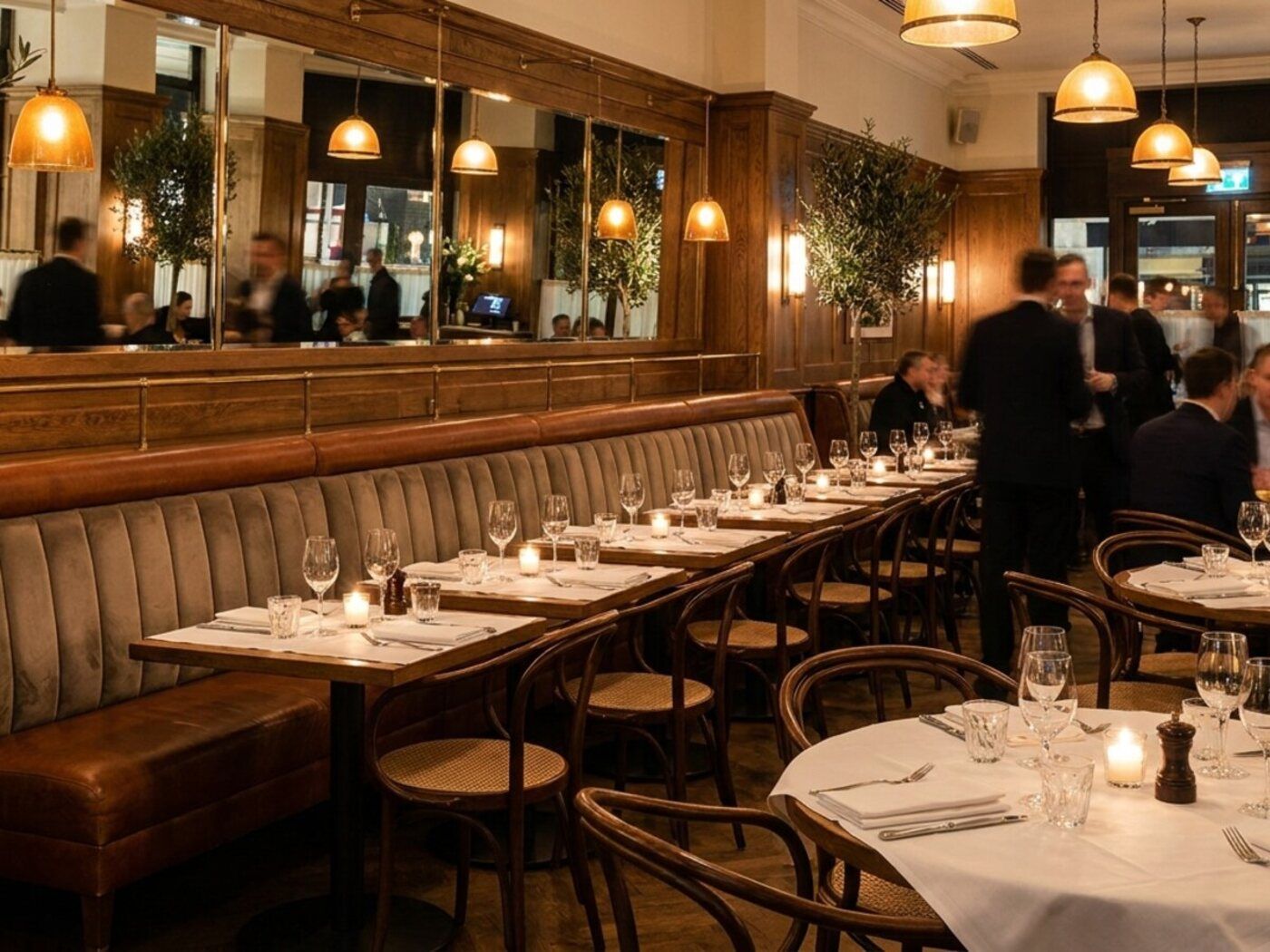 Op maat gestoffeerde wandbank in een restaurant met gedekte tafels